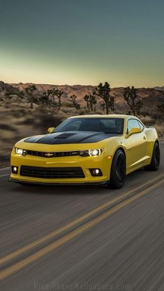 a yellow chevrolet camaro is driving down the road