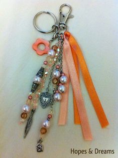 a keychain with some charms attached to it's sides and an orange ribbon