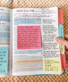 an open bible with sticky notes attached to the pages, and someone holding one in their hand