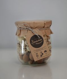 a jar filled with lots of nuts on top of a white table next to a tag