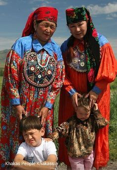 three people in colorful clothing standing next to each other on a dirt road with grass and blue sky behind them