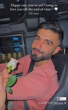 a man sitting in the back seat of a car holding a rose with a message written on it