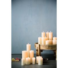 a bunch of lit candles sitting next to each other on a wooden table in front of a blue wall