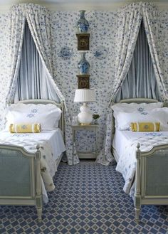 two beds in a room with blue and white wallpaper