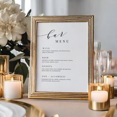 a table setting with candles, flowers and menu cards in gold frames on the table