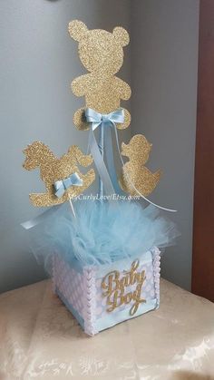 a blue and gold baby shower cake in a gift box with some decorations on top