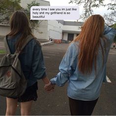 two girls walking down the street holding hands and one has a backpack on her back