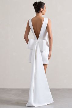 the back of a woman wearing a white dress with a large bow at the waist