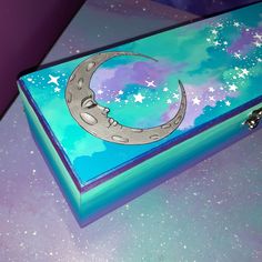 a painted box sitting on top of a table with stars and the moon in the sky