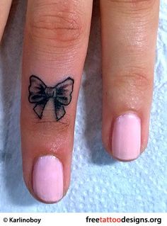 a woman's finger with a bow tattoo on it