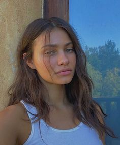 a young woman standing next to a window