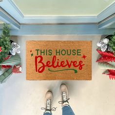 someone standing in front of a door mat that says, this house believes