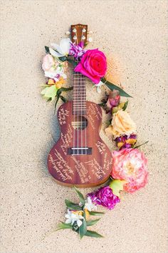 a ukulele with flowers and writing on it sitting next to a flower arrangement