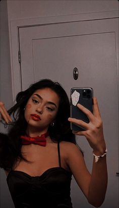 a woman taking a selfie in front of a mirror wearing a red bow tie