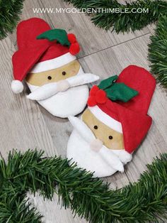 two christmas decorations made out of felt on top of a wooden floor with pine branches