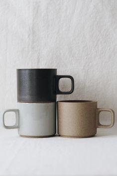 two black and white coffee mugs sitting next to each other on top of a table