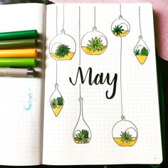 an open notebook with some plants hanging from it and the word may written in cursive writing