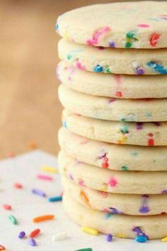 a stack of white cookies with sprinkles and rainbow colored confetti