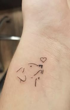 a small wrist tattoo with a dog's head and heart on the left side