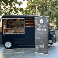 the food truck is parked on the side of the street with its menu in front of it