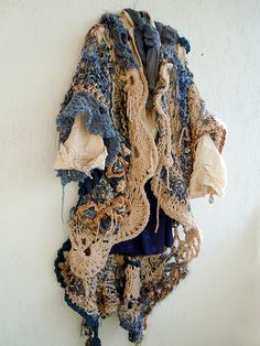 a pile of clothes hanging on the side of a wall next to a white wall