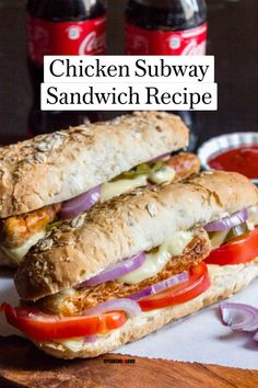 chicken subway sandwich with red onions and tomatoes on a cutting board next to two bottles of soda