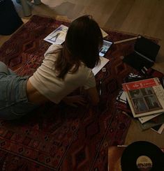 a woman is sitting on the floor with her laptop and papers in front of her