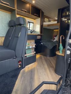 the interior of an rv with wood flooring and black leather seats, bookshelves