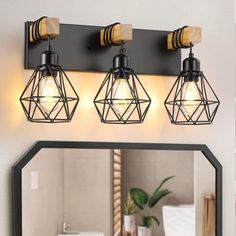 a bathroom vanity with three lights and a mirror on the wall next to it,