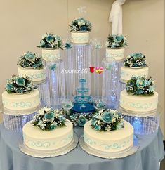 a table topped with lots of cakes covered in frosting and blue flowers on top of each cake