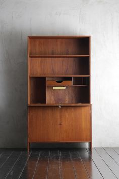 a wooden bookcase sitting on top of a hard wood floor next to a wall