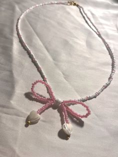 a pink and white beaded necklace with bells