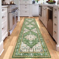 a green rug in the middle of a kitchen with white cabinets and drawers on both sides