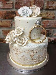 a wedding cake decorated with white flowers and gold rings