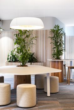 a table and stools in a room with plants on the wall behind it,