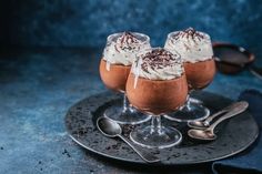 three glasses filled with dessert sitting on top of a plate