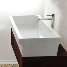 a white sink sitting on top of a wooden counter next to a wall mounted faucet