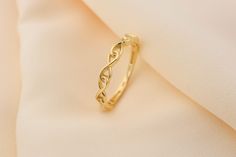 a gold wedding band on top of a white cloth with the word love written in cursive writing