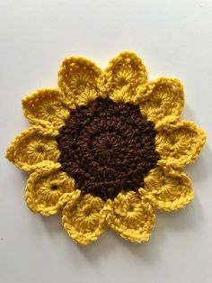 a crocheted sunflower is shown on a white surface with brown and yellow accents