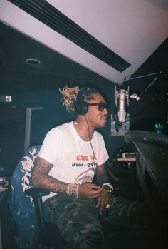 a young man sitting in front of a microphone wearing headphones and listening to music