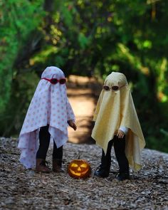 two dolls dressed in costumes stand next to a pumpkin