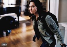 a woman is walking down the hall in a room with wood flooring and furniture