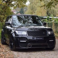 a black range rover parked on the side of a road in front of some trees