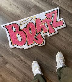 someone standing on the floor next to a door mat that says boraz in pink and yellow