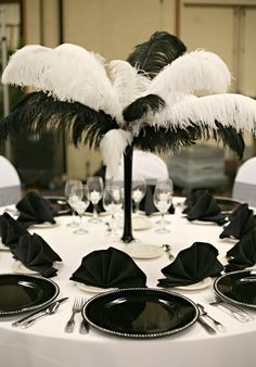 the table is set with black and white plates, silverware, and palm tree centerpieces