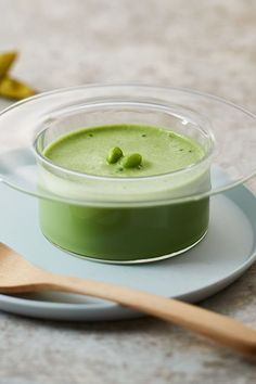 a small bowl filled with green liquid on top of a plate