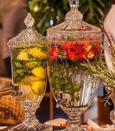 two glass vases filled with different types of fruit and veggies on top of a table