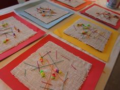 the table is set up with four different square pieces of art made out of burlap