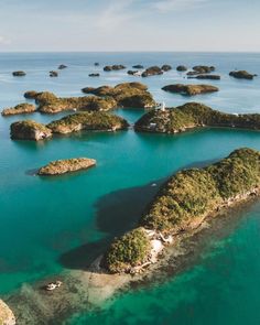 an aerial view of several small islands in the ocean with clear blue water and green vegetation