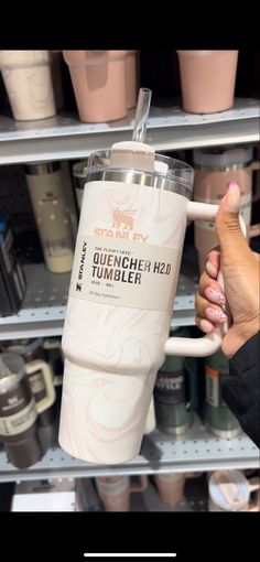 a person is holding a coffee cup in front of shelves